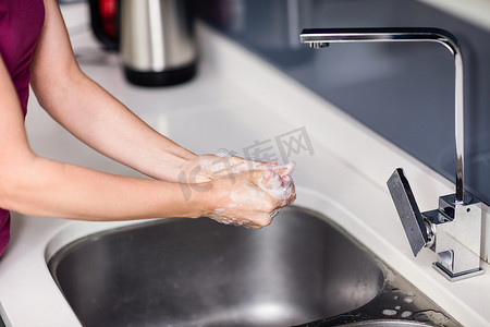 妇女在水槽洗手的裁剪图像