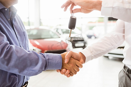 钥匙男人摄影照片_商人在与顾客握手时给车钥匙