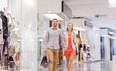 抖音赠送摄影照片_快乐的年轻夫妇在商场里提着购物袋