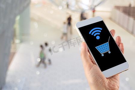 带手持智能手机购物车 wi-fi 的模糊散景购物中心
