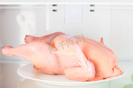 架子肉摄影照片_冰箱架子上的生鸡肉，盘子特写