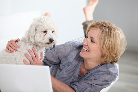 带着狗和笔记本电脑微笑的女人