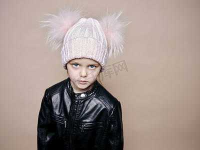 皮夹克摄影照片_戴着羊毛帽和皮夹克的漂亮小女孩的画像