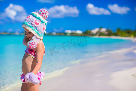 沙滩上戴着温暖针织帽和手套的可爱小女孩