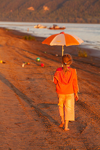 阳光下沿着沙滩奔跑的小女孩