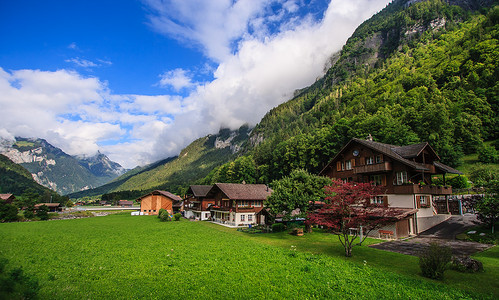阿尔卑斯山风景如画的乡村山景的美丽全景明信片视图与传统的古老高山山区小屋和新鲜的绿色草地在阳光明媚的日子与蓝天和云彩在夏天。