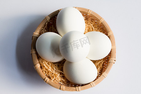 白色鸭蛋摄影照片_在白色背景的篮子柳条中的鸡蛋，在篮子中的鸭蛋。