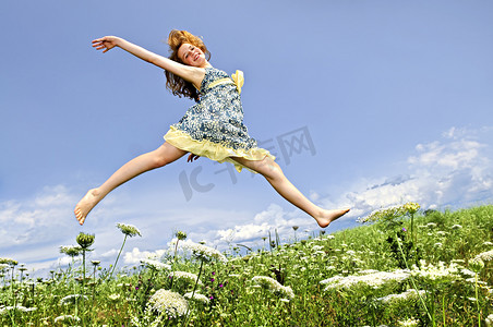 年轻的女孩在草地上跳跃