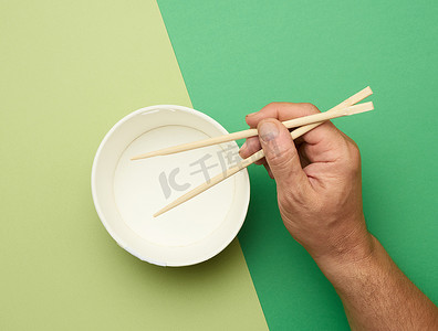 男性手中的一双木筷和空纸盘 o