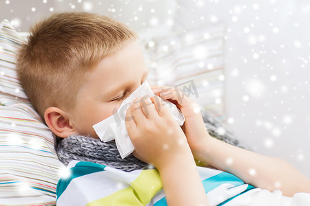 鼻涕摄影照片_生病的男孩在家里用纸巾擤鼻涕
