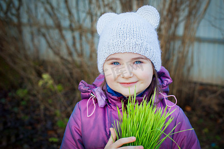 美丽的微笑女孩拿着绿草，看着镜头