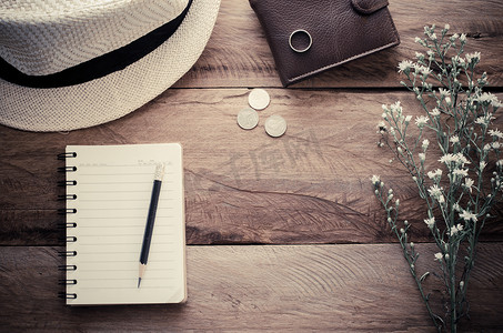 笔记本铅笔帽钱包硬币和木桌上的花-色调复古。