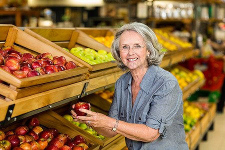 高级超市摄影照片_微笑的高级女人摘苹果
