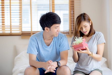 美丽的年轻亚洲夫妇在卧室里的爱情惊喜礼盒