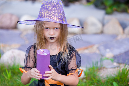 万圣室外摄影照片_万圣节和可爱的小女孩带着蜡烛装扮成女巫