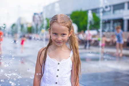 小女孩在炎热的天气里在户外喷泉里玩得开心