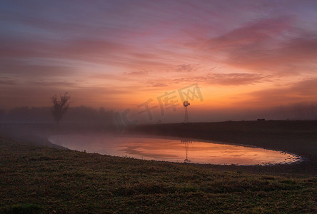 农村湖水摄影照片_黎明时的红色天空，轻雾笼罩着农村农田
