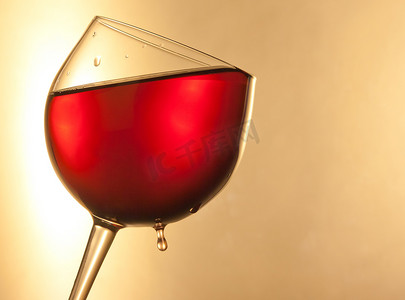 玻璃杯中的红酒倾斜着金色的水滴和文字空间