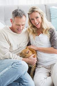 沙发猫摄影照片_微笑的夫妇在地毯上抚摸他们的格林杰猫