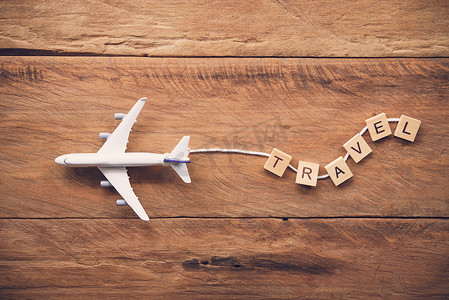 带有文字“旅行”的飞机放在木地板上。
