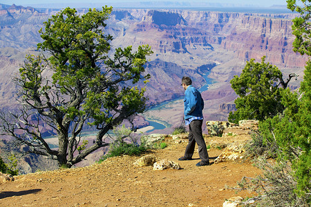 亚利桑那的阳光摄影照片_四十多岁的白人男子小心翼翼地看着 Gr 的悬崖