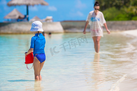 家庭度假摄影照片_海滩度假期间的小女孩和快乐的母亲