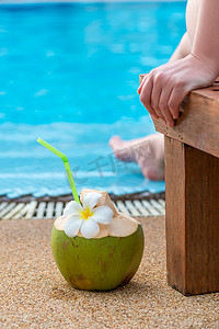 游泳池附近躺椅上的女人和靠近一根稻草的椰子