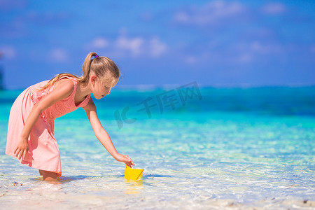 可爱的小女孩在绿松石海中玩折纸船
