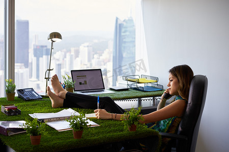 环保女性赤脚在办公桌上写字条
