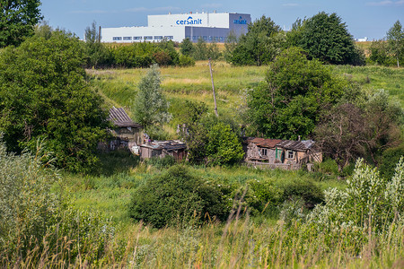 一座巨大的厂房背景下的一座旧农村房屋的废墟