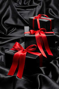 黑色缎面摄影照片_“带红色缎带和蝴蝶结的黑色礼盒，覆盖黑色缎面”