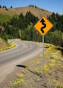 道路标志指示前方山地景观的曲线