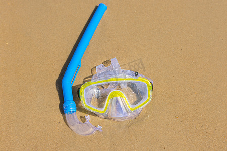 游泳面罩和呼吸管在水下呼吸，躺在海岸的湿沙上