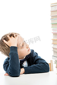 一个疲惫的男孩的肖像，桌上放着一堆书，与世隔绝