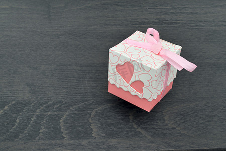 粉红蝴蝶结摄影照片_带粉红心的白色小礼盒和带粉红蝴蝶结的丝带