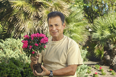 一个快乐的人在花园里拿着花卉植物的肖像