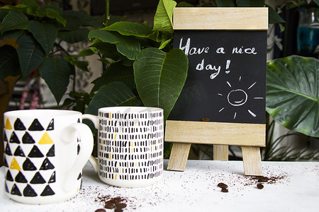 愉快的一天摄影照片_咖啡豆、杯子，在黑板上度过愉快的一天文字和字母，在自然背景下拍摄