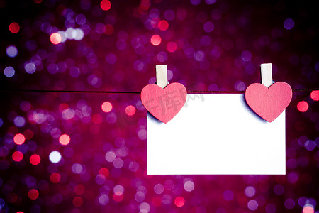 蓝色和紫色浅色背景上挂着贺卡的两颗装饰性红心，情人节的概念