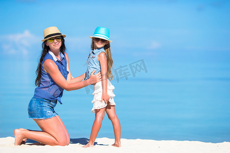 家庭度假摄影照片_海滩度假期间的小女孩和年轻母亲