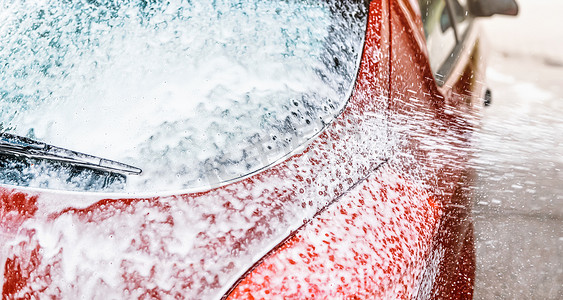 洗车时，汽车后窗的细节上覆盖着肥皂泡沫，刷子喷得更多