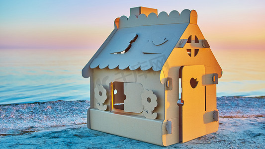 日落时在海岸用瓦楞纸板制成的玩具屋。