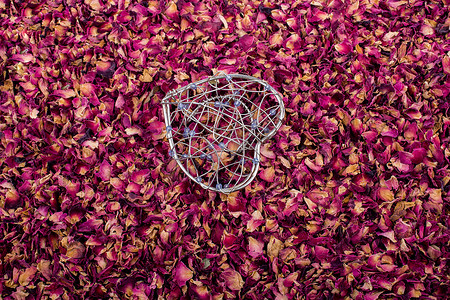 心形玫瑰花瓣摄影照片_干燥玫瑰花瓣上的心形笼子