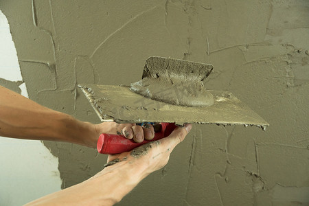 一名工人用抹刀抹墙，并涂上水泥 m