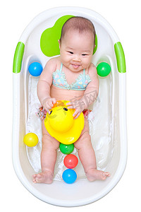 亚洲女婴在白色浴缸里洗澡玩鸭子