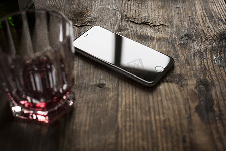 手机黑色苹果手机摄影照片_在木桌上的智能手机用威士忌酒