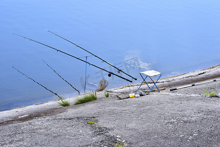 湖边带钓鱼竿和钓鱼设备的椅子
