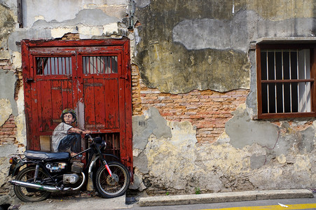 马来西亚槟城摄影照片_马来西亚槟城-2016 年 4 月 18 日：欧内斯特·扎查雷维奇 (Ernest Zacharevic) 绘制的壁画《骑自行车的男孩》的全景。