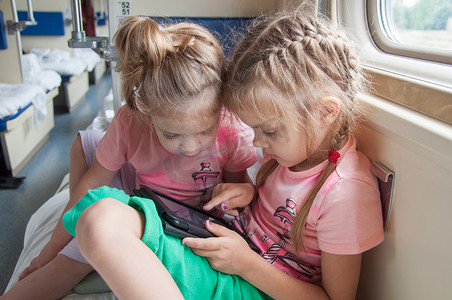 两个女孩在火车二等座平板电脑上玩耍