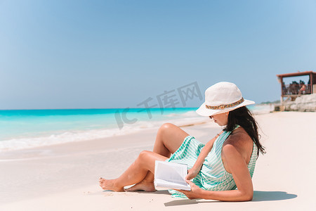 年轻女子在沙滩躺椅上看书
