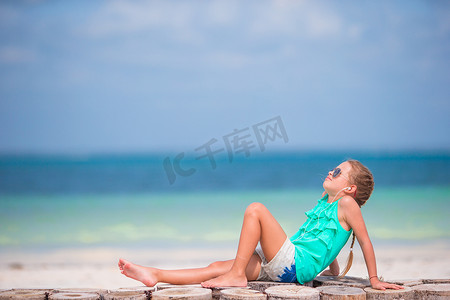 小女孩在沙滩上戴着耳机听音乐
